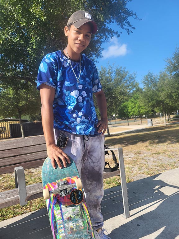 Skater holding skateboard while smiling.